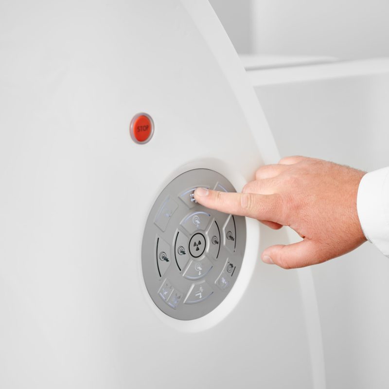 Close up of radiologist making MRI for patient. Male specialist wearing white robe, pressing button by finger, working in hospital. Concept of healthcare and modern diagnostics.